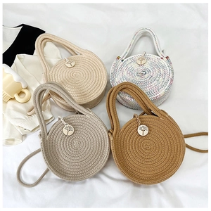 Détail de quatre sacs en paille tissée avec breloques en bois et fermeture éclair