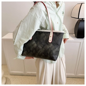 Détail du sac cabas gris foncé à motif matelassé avec bandoulière blanche et boucles dorées