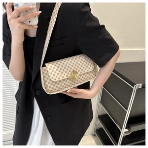 Modèle portant un sac bandoulière vintage à motifs marrons et fermoir rotatif doré