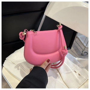 Detailed close-up of a bright pink mini leather shoulder bag with golden zipper and knotted strap