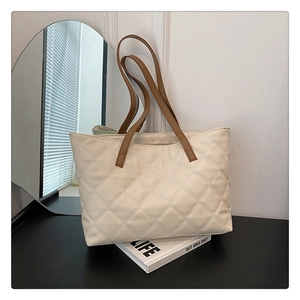 Detailed view of beige quilted tote bag with brown straps and diamond stitching