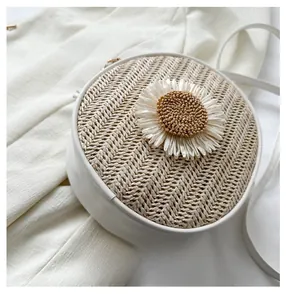 Détail du sac bandoulière rond en paille avec motif marguerite et texture tressée