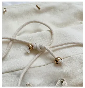 Detailed close-up of straw bucket bag with gold hardware and woven drawstring closure