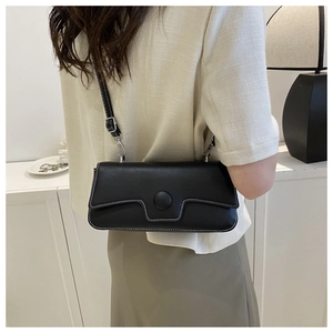 Detail view of black rectangular crossbody bag featuring contrast white stitching