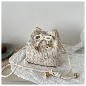 Close-up of woven straw bucket bag with delicate daisy embroidery and drawstring detail
