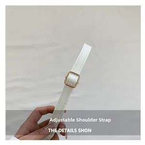 Détail d'une bandoulière réglable en cuir synthétique blanc avec boucle dorée