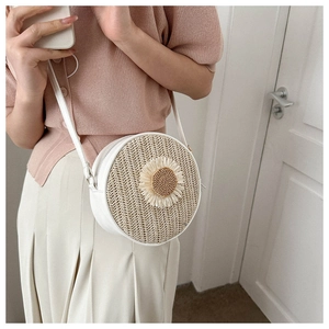 Détail d'un sac bandoulière rond en paille tressée avec fleur marguerite et fermeture éclair