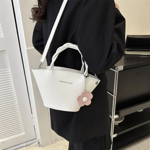Minimalist white leather bucket bag with woven handle and pink flower charm on a model