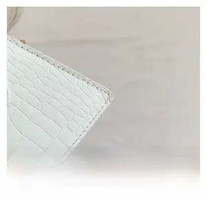 Détail de la texture en simili cuir crocodile blanc et coutures soignées sur un petit sac