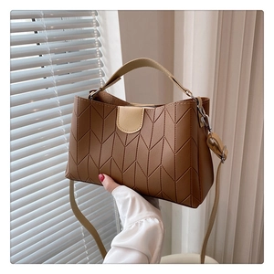 Detail of brown tote bag featuring V-shaped geometric stitching and premium PU straps