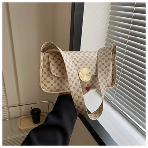 Détail d'un sac porté épaule beige imprimé avec boucle dorée circulaire et large bandoulière