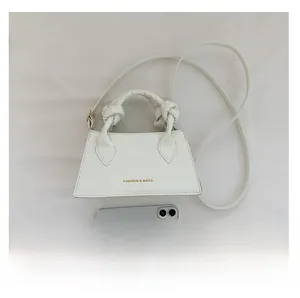 Détail du sac à main blanc à motif crocodile avec téléphone pour échelle de taille