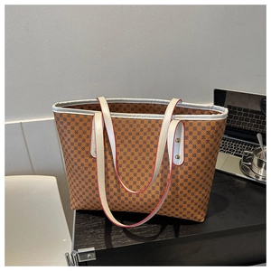 Detail view of brown tote bag with geometric print and white straps on a desk