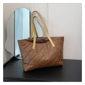 Detailed view of caramel brown quilted tote bag with cream-colored thin handles
