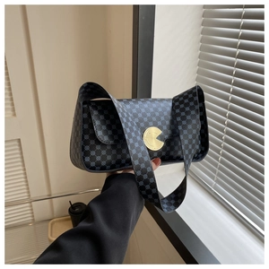 Détail du sac à bandoulière noir vintage avec motif à pois bleus et boucle en métal doré