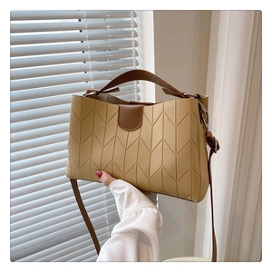 Detail of a chic tote bag with V-shaped stitching and contrasting brown leather straps