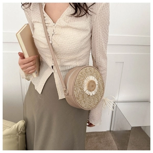 Détail d'un sac bandoulière rond en paille avec une marguerite blanche en relief en 3D