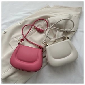 Detail of pink and white saddle handbags with knotted straps and gold hardware