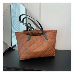Detail of brown quilted leather tote bag with elegant diamond stitching and black handles