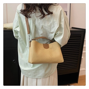 Detail view of snakeskin pattern contrast handbag with brown leather strap on shoulder