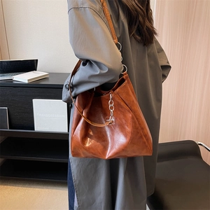Grand sac fourre-tout marron avec chaîne argentée porté par un mannequin au bureau