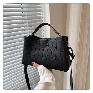 Detail of black faux leather tote bag showing stylish V-shaped quilted stitching and silver hardware