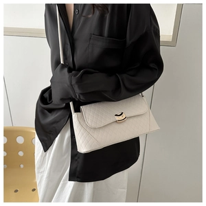 Détail du sac sous le bras matelassé blanc avec boucle en métal doré sur le rabat