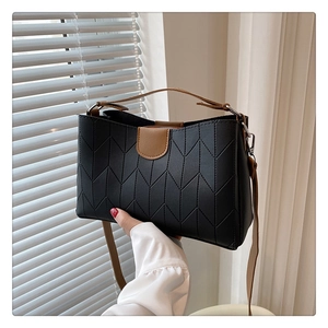 Detail of black V-quilted handbag with brown leather strap and top zipper closure