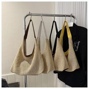 Détail de sacs cabas en paille tissée avec bandoulières noires, marron, jaunes et blanches