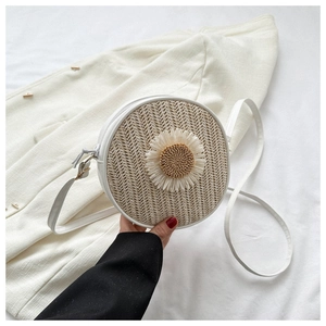 Détail d'un sac rond en paille tressée avec marguerite blanche et zip métallique