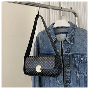 Détail d'un sac bandoulière vintage à monogramme avec boucle dorée et veste en jean bleue