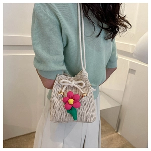 Detailed texture of hand-woven straw bucket bag with 3D pink floral accent