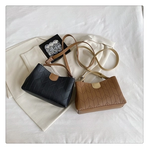Close-up of black and brown PU leather crossbody bags with chic herringbone stitching