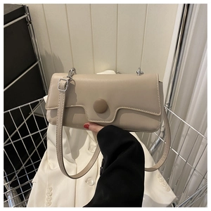 Detailed close-up of beige faux leather baguette bag with a circular decorative buckle