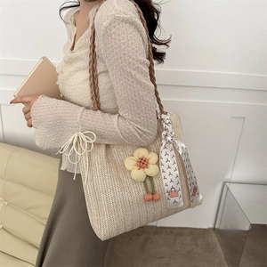 Fashionable beige woven straw tote bag with floral charm and patterned silk scarf detail
