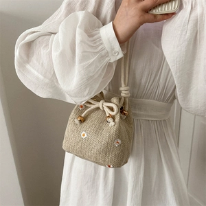Handwoven straw bucket bag with white daisy embroidery and drawstring closure