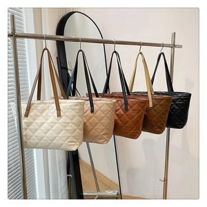 Collection of quilted tote bags in five neutral colors displayed on a modern metal rack