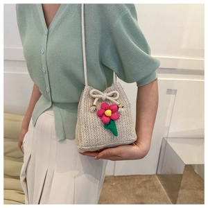 Detail of straw bucket bag with pink crochet flowers and white drawstring closure