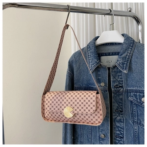 Détail d'un sac sous le bras imprimé rose avec boucle dorée et veste en jean