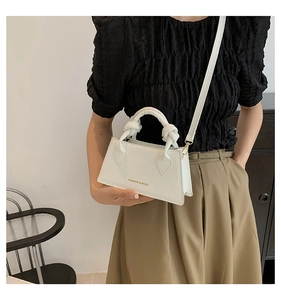 Détail du sac à main blanc gaufré crocodile avec poignée nouée et lettrage doré