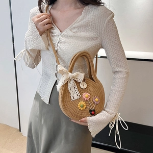 Sac bandoulière en paille d'été avec fleurs et nœud en dentelle sur un mannequin