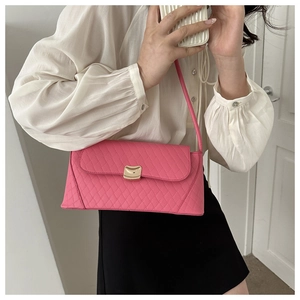 Détail du sac bandoulière rose matelassé avec fermoir doré sur chemise blanche