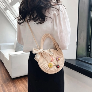 Sac à main en paille avec fleurs 3D et nœud en dentelle porté par un mannequin