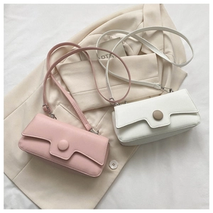 Detail of minimalist faux leather shoulder bags in soft pink and white with round buckle