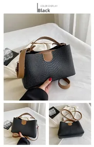 Close-up of black embossed snake texture leather with brown top handles and long strap