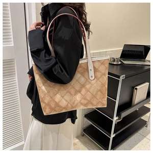 Détail d'un grand sac cabas matelassé beige avec anses blanches et finitions de bords rouges