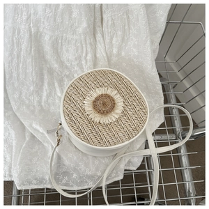 Détail d'un sac cylindrique tressé avec décor tournesol dans un panier métallique