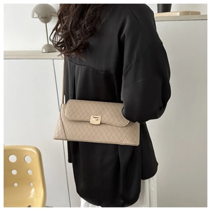 Détail du sac bandoulière matelassé beige avec fermoir doré porté par un mannequin