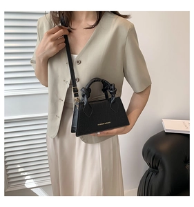 Détail du mini sac à main noir texture crocodile avec texte doré et poignées nouées