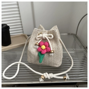 Detail of beige straw bucket bag with pink floral accents and cotton rope strap
